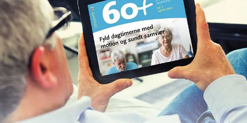 En ældre mand sidder og læser seniorbladet 60+ på sin iPad.