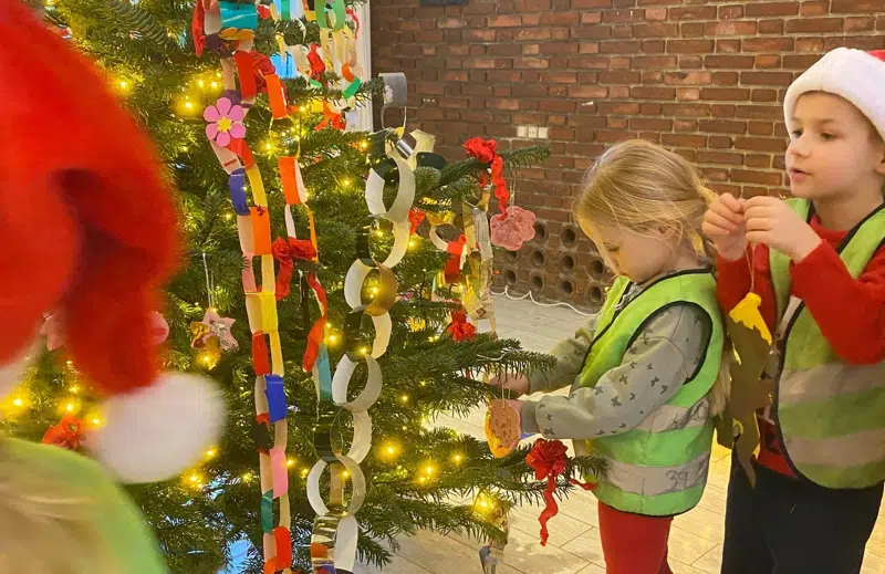 En dreng og en pige pynter træet i rådhusets forhal