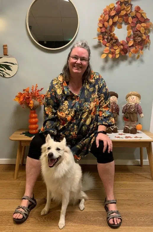  En kvinde sidder på en bænk med en hvid hund foran sig