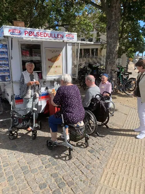 fire beboere fra Egegården ses foran en pølsevogn