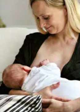 Den klassiske ammestilling, hvor mor sidder op og barnet ligger på tværs henover mors mave og hovedet hviler på mors underarm