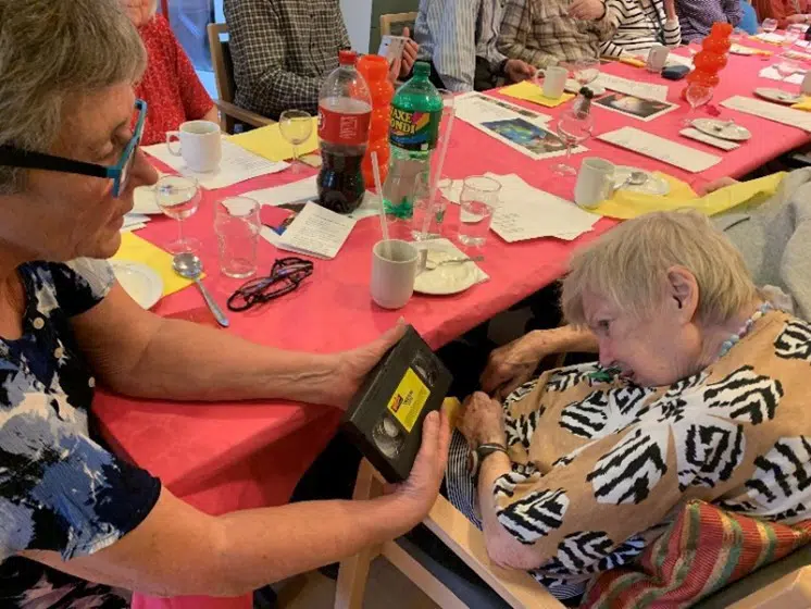 En kvinde viser en ældre kvinde et VHS-bånd