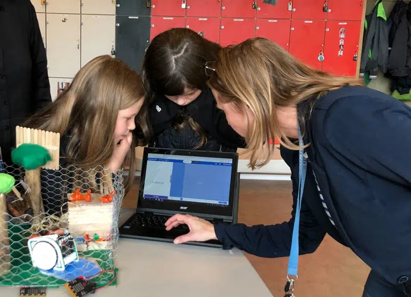 Elever og lærer kigger på en computer