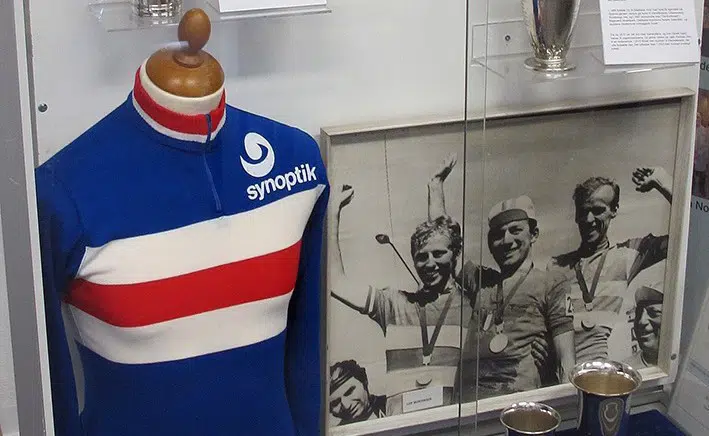 En udstillingsmontre med billeder, pokaler og en cykeltrøje.