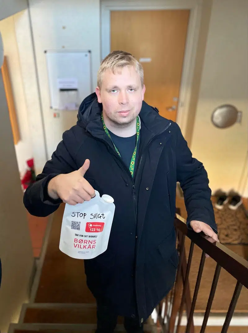 Hverdagsaktivist med indsamlingsbøsse for Børns Vilkår i en opgang.