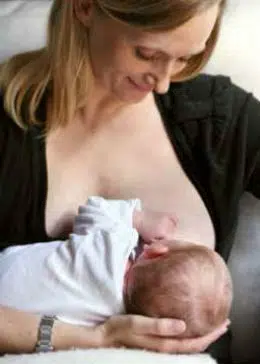 Krydsstilling, hvor mor sidder op og barnet ligger på tværs hen over mors mave, samtidig med at mor støtter barnets krop med sin underarm og hovedet hviler i mors hånd