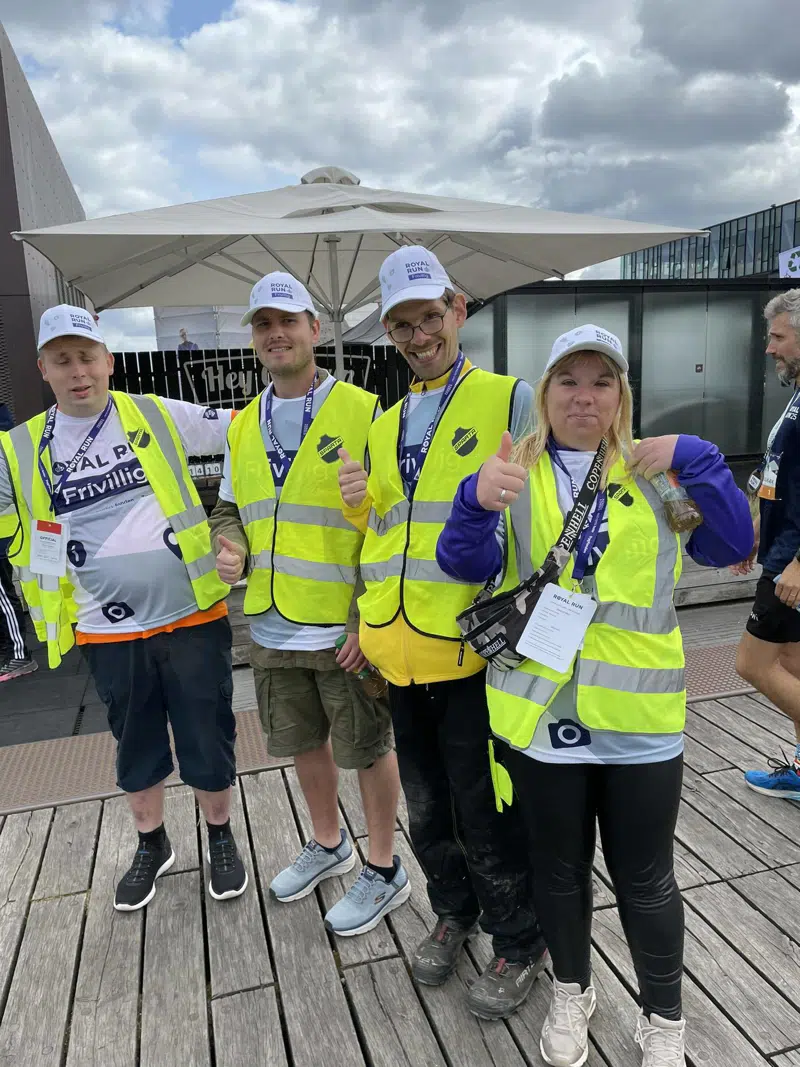 Fire glade hverdasaktivister, der er er iført kasketter og veste, der gør det synligt, at de er frivillige.