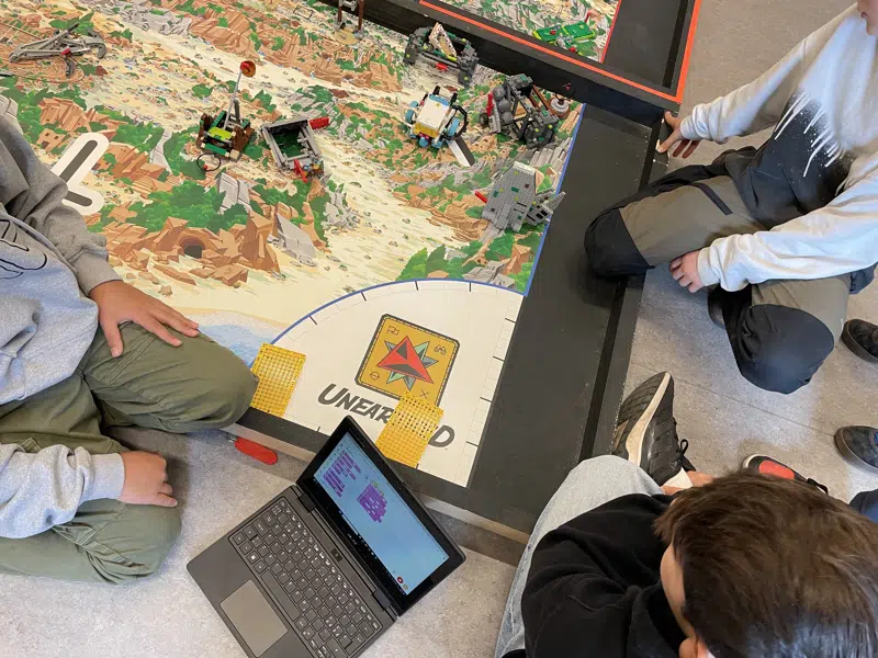 Unge sidder med LEGO og en computer og er i gang med at programmere robotter.