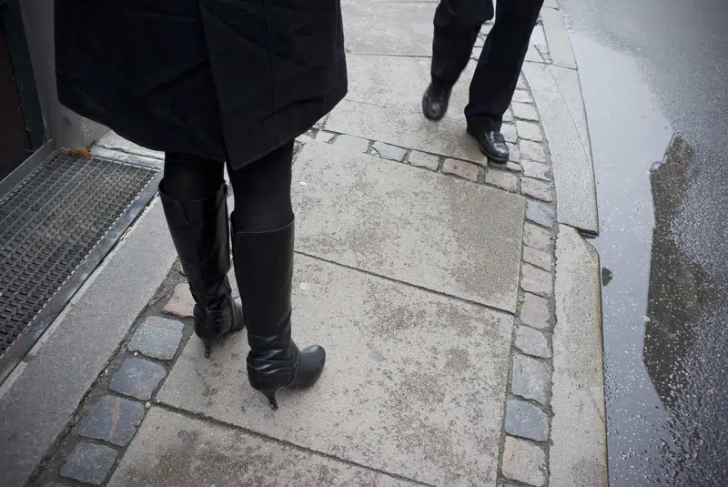 Herre og dame der passere hinanden på fortorv. Man kan kun se deres fødder.
