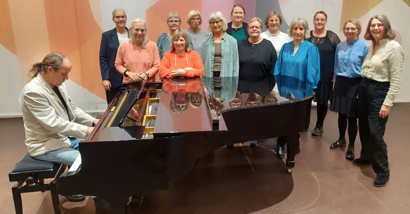 Medlemmerne af Kolding Rytmiske Kor omkring et flygel