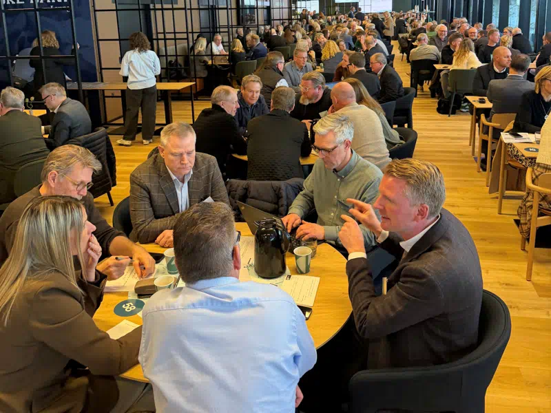 Erhvervsfolk omkring et bord, som taler sammen