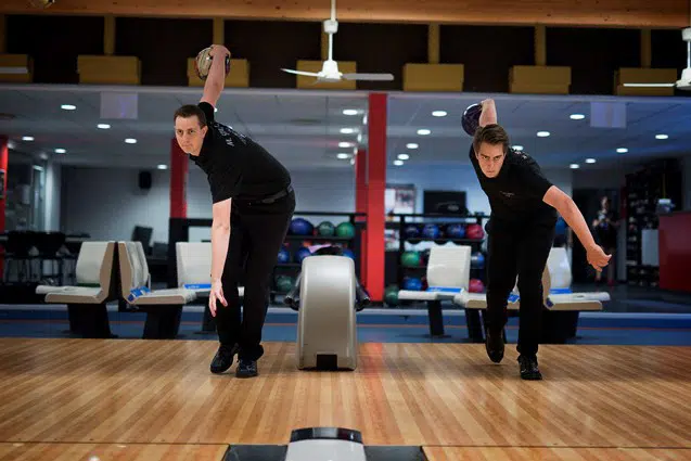 To bowlingspillere er i færd med at kaste bowlingkugler afsted