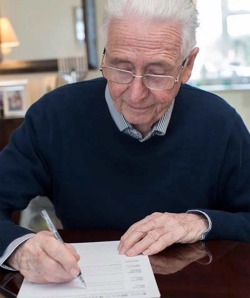 Ældre herre skriver med kuglepen på et dokument