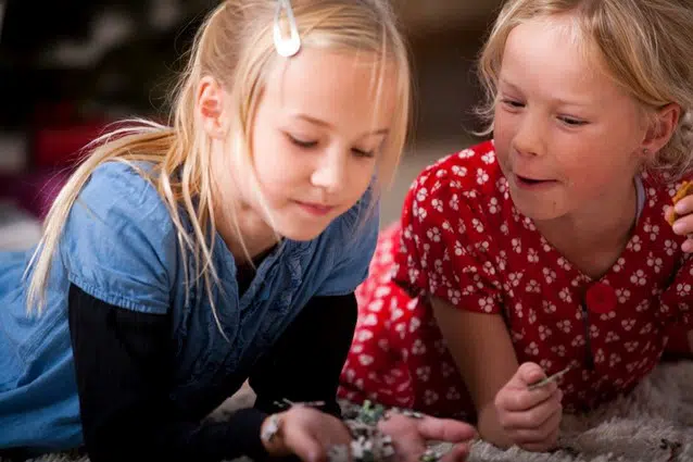 To piger der ligger på gulvet og laver puslespil