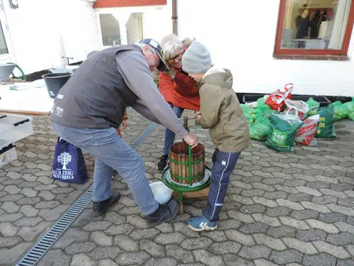 To voksne og et barn betjener en pressemaskine