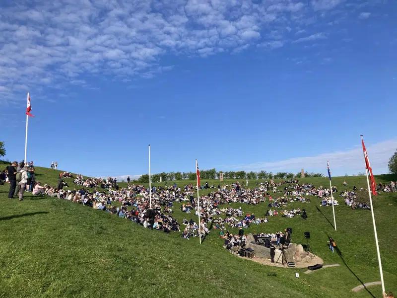 Skoleelever sidder på græsset på Skamlingsbanken