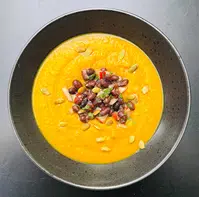 Cremet græskarsuppe toppet med sorte bønner, koriander og æble