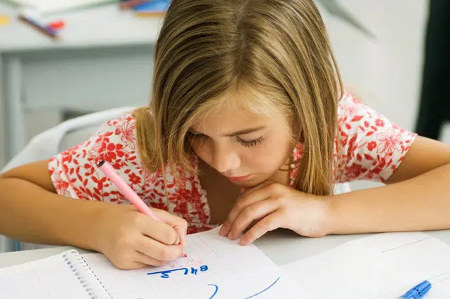 En ung pige, der skriver på et stykke papir