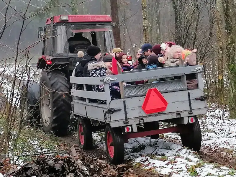 Børn og voksne i åben vogn efter en traktor