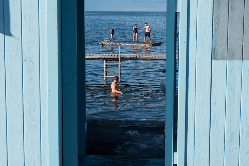 Foto - kig ind igennem badeanstaltens karakteristiske lyseblå træhegn til badegæster på broerne
