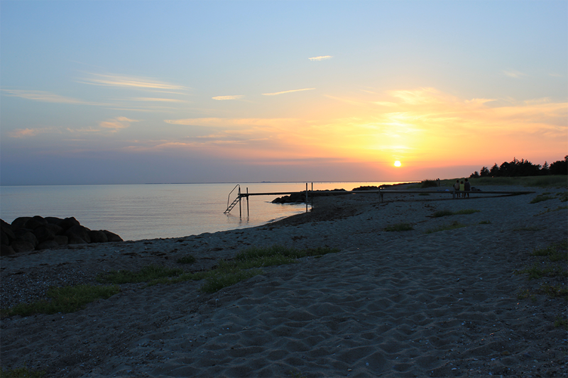 Foto af solnedgang over strandbred og badebro