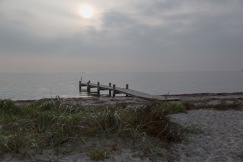 Foto af strandbred med badebro i aftenlys