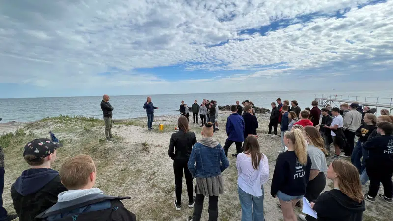 en gruppe mennesker, der står på en strand