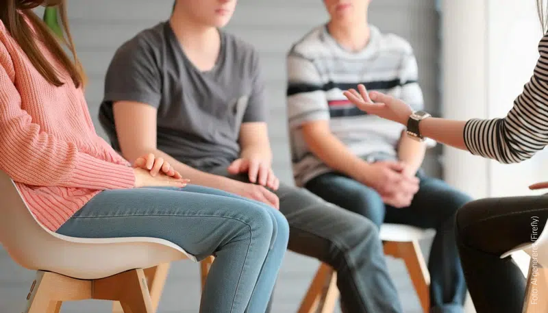 Fire personer sidder på stole og snakker