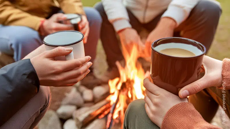 Fire personer sidder rundt om et bål