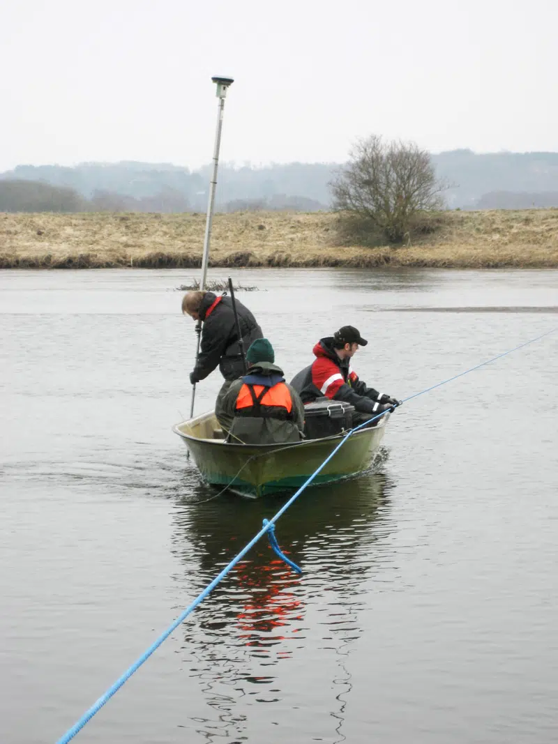 Teknikere, der opmåler åens dybde fra båd