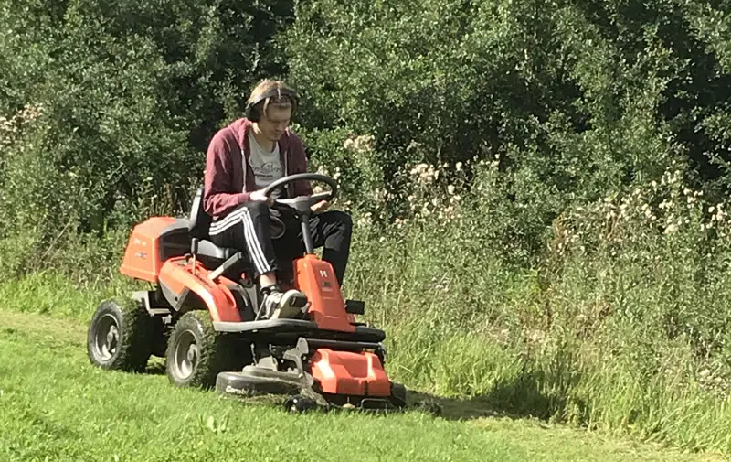 Elev slår græs med havetraktor.